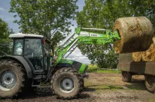 Ładowarcz Intertech IT 1600 z ciągnikiem Deutz Fahr podczas załadunku bel słomy na przyczepę z niewielkiego stogu.