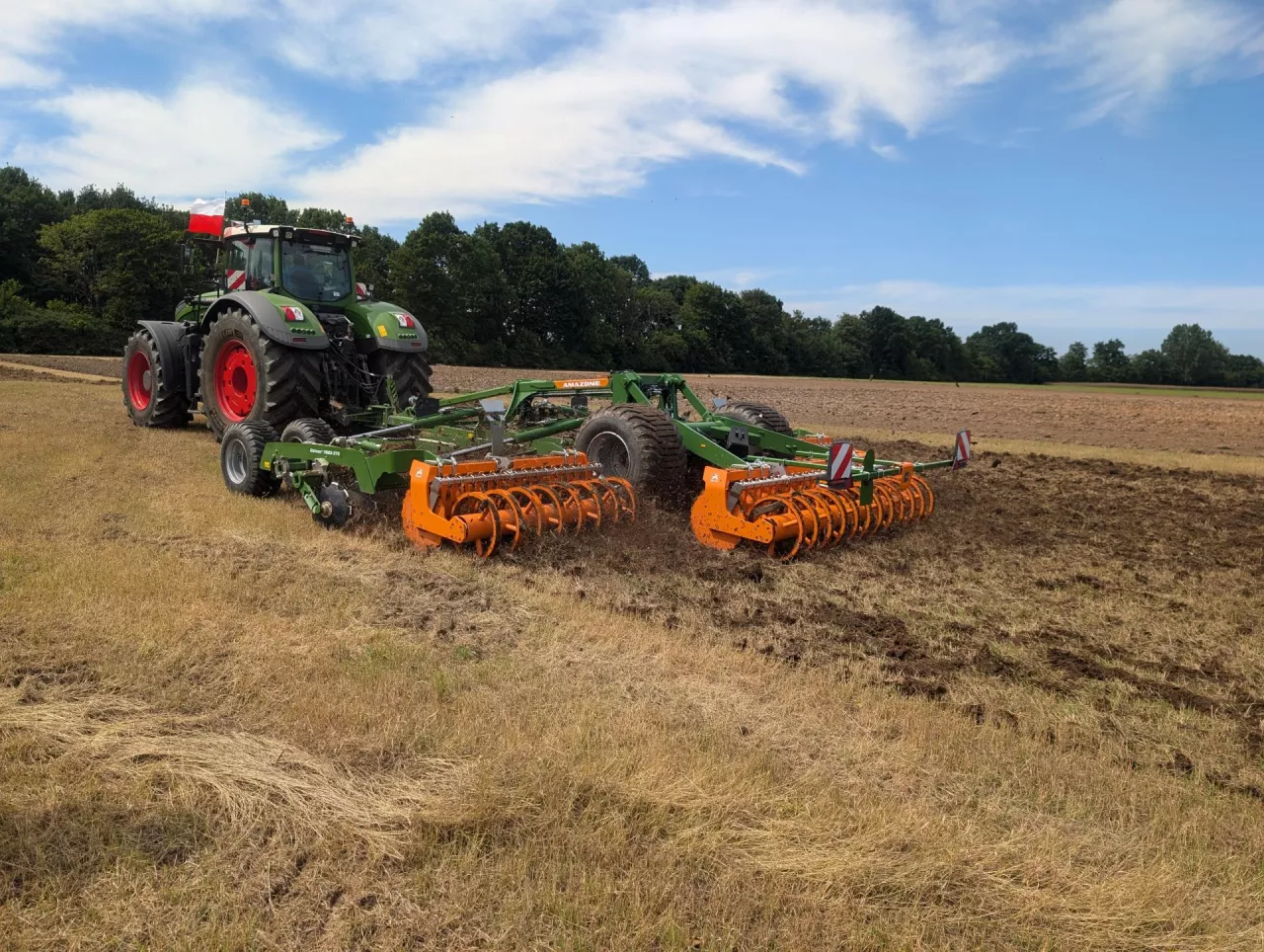 Zdjęcie przedstawia nowoczesny ciągnik rolniczy Fendt z agregatem uprawowym Amazone podczas pracy w polu. Widoczna na zdjęciu polska flaga podkreśla lokalny charakter gospodarstwa. Ilustracja modernizacji i wysokiego poziomu technicznego polskiego rolnictwa