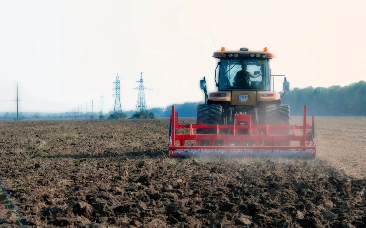 Ciągnik z przyczepionym agregatem uprawowym jedzie przez pole